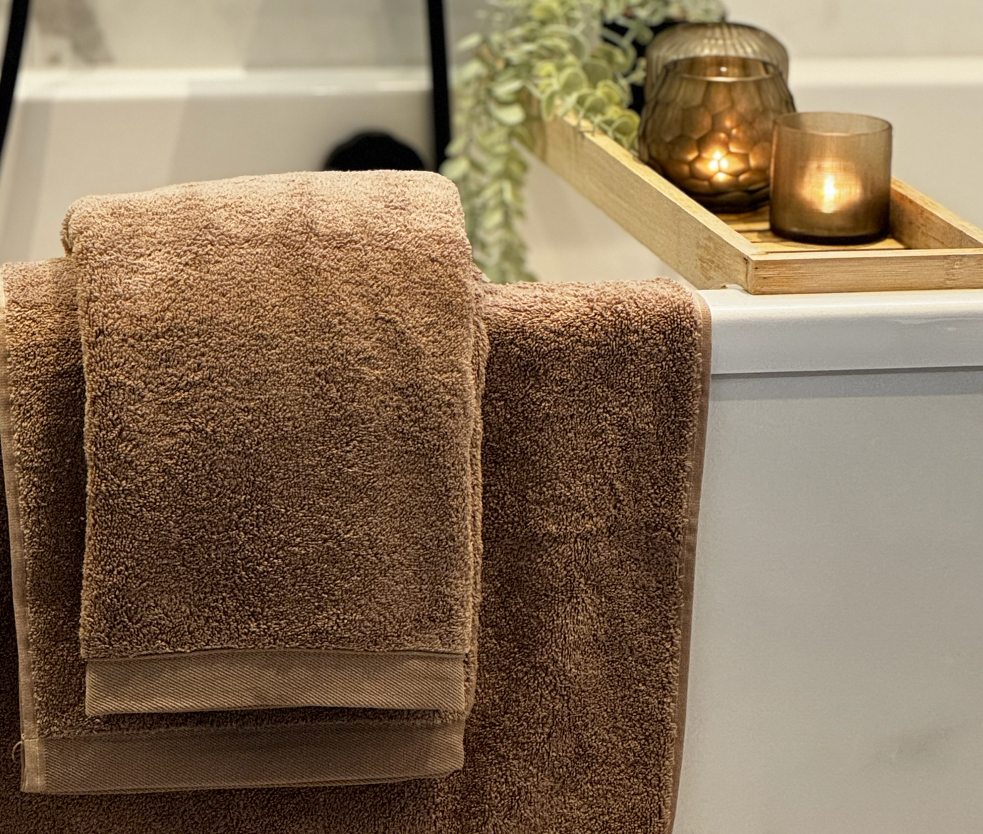 Bruine dikke hotel handdoeken die over een badrand hangen